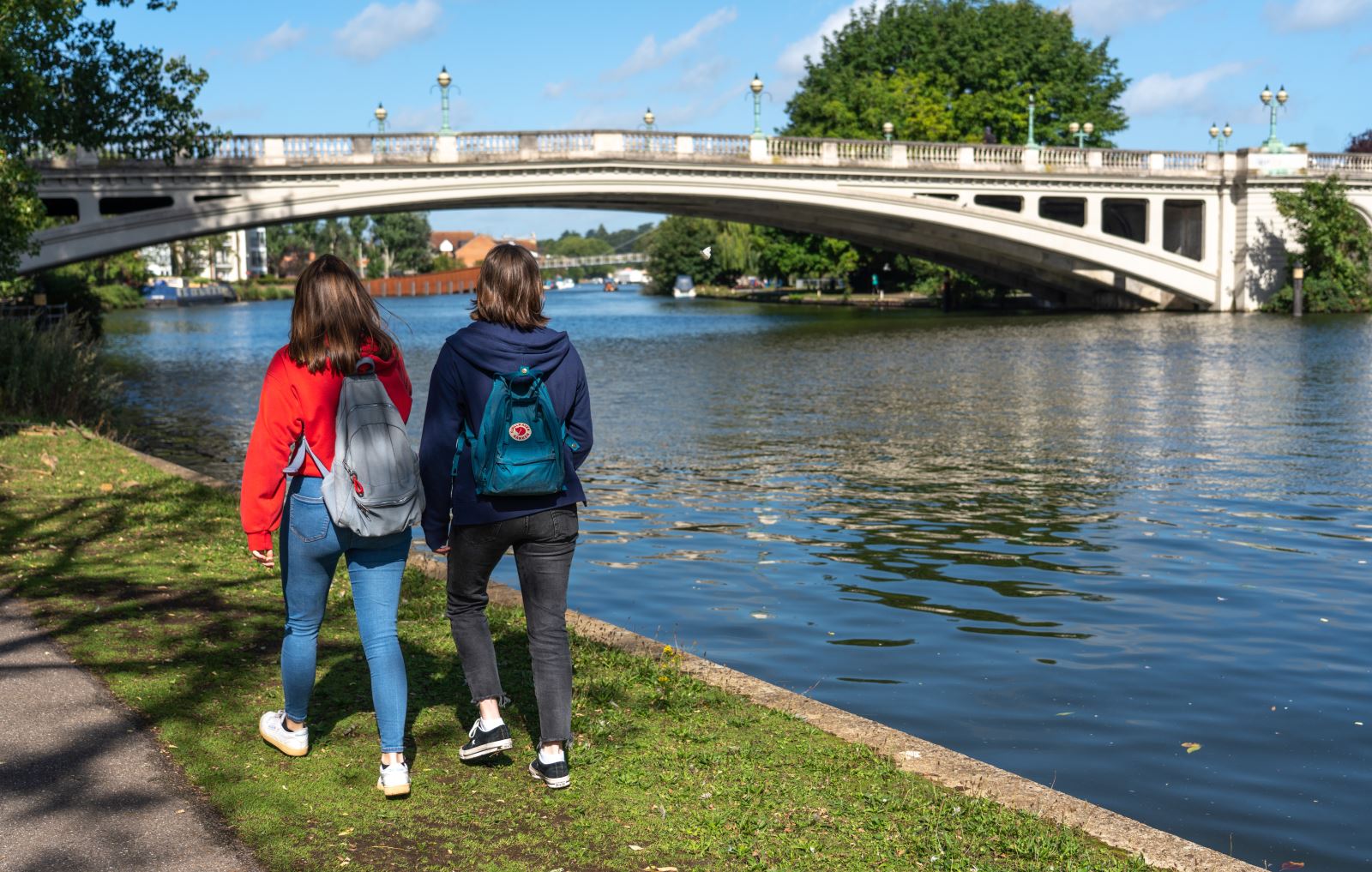 Two girls walking by a river